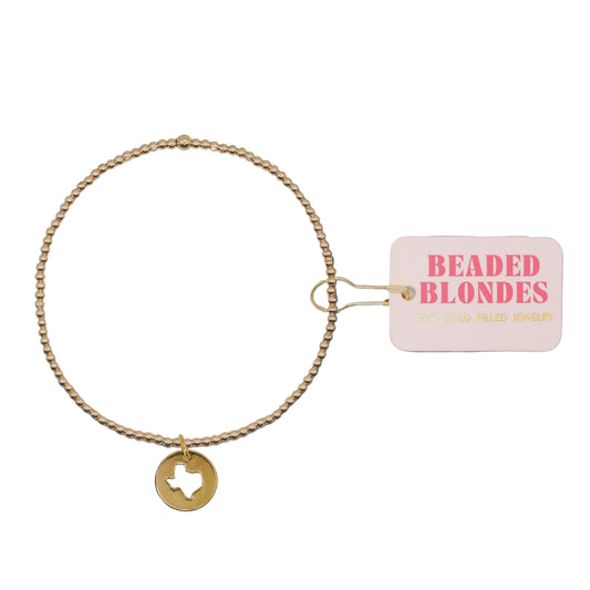 Gold bracelet with a Texas charm and 'Beaded Blondes' tag on a white background