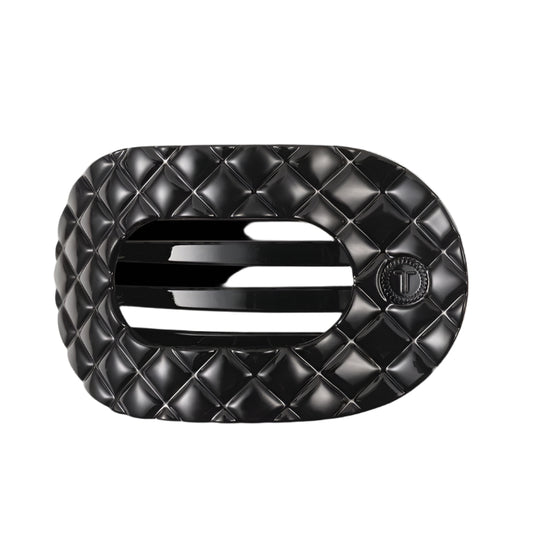 Black quilted hair clip with a brand logo on a white background
