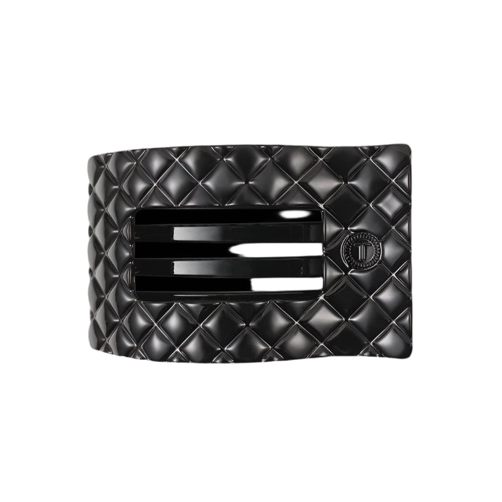 Black quilted hair clip with a brand logo on a white background

