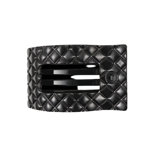 Black quilted hair clip with a brand logo on a white background

