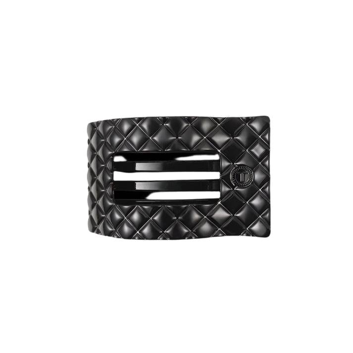 Black quilted hair clip with a brand logo on a white background
